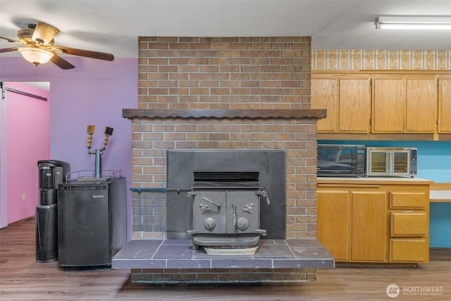 4901 Delta Ln SE, Tumwater, WA 98501 - living area with light wood-style floors, a ceiling fan, and a wood stove