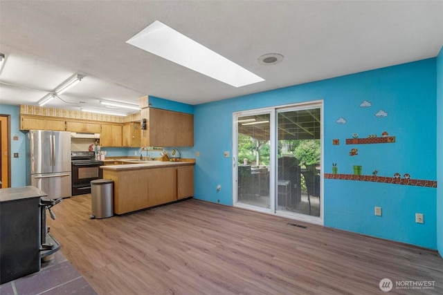 4901 Delta Ln SE, Tumwater, WA 98501 - kitchen featuring black electric range, freestanding refrigerator, a skylight, light wood finished floors, and under cabinet range hood