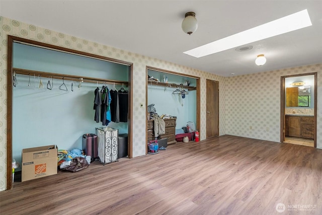 4901 Delta Ln SE, Tumwater, WA 98501 - bedroom with a skylight, wallpapered walls, wood finished floors, two closets, and ensuite bath