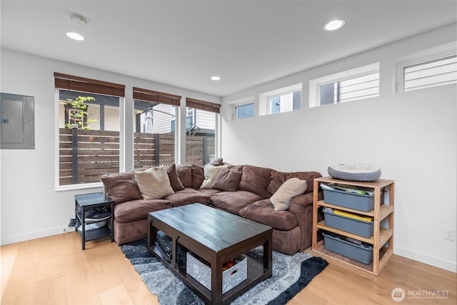 living area with recessed lighting, baseboards, electric panel, and light wood-type flooring
