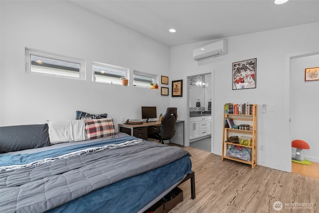 bedroom with light wood-style floors, recessed lighting, ensuite bathroom, and a wall mounted AC