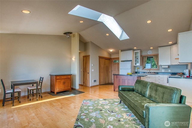 living area with recessed lighting, visible vents, lofted ceiling with skylight, light wood-type flooring, and baseboards