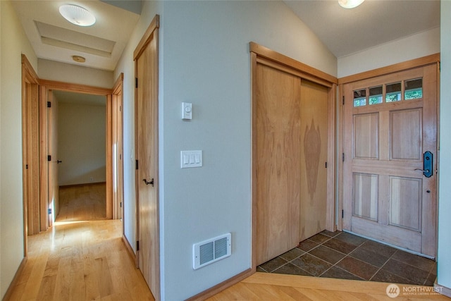foyer featuring vaulted ceiling, wood finished floors, and visible vents
