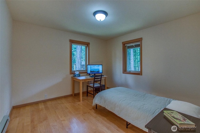 bedroom with a baseboard radiator, wood finished floors, and baseboards