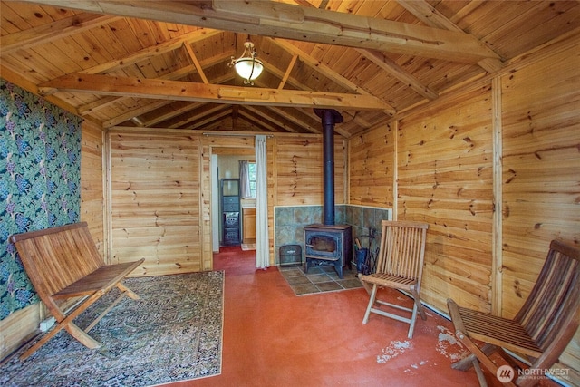 unfurnished room with wood walls, a wood stove, and vaulted ceiling