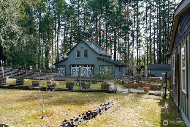 rear view of property featuring an outdoor structure, fence, a detached garage, a vegetable garden, and a yard