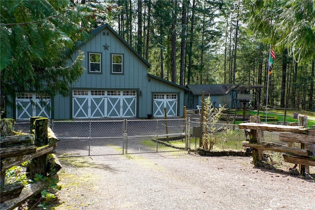 view of front facade featuring driveway, a gate, fence, and board and batten siding