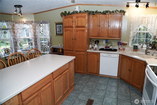 kitchen with white appliances, brown cabinetry, a sink, and a textured ceiling