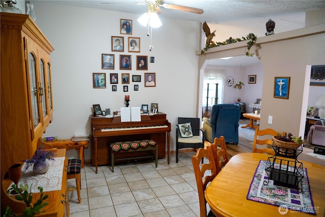 dining area with arched walkways, light tile patterned floors, and a ceiling fan