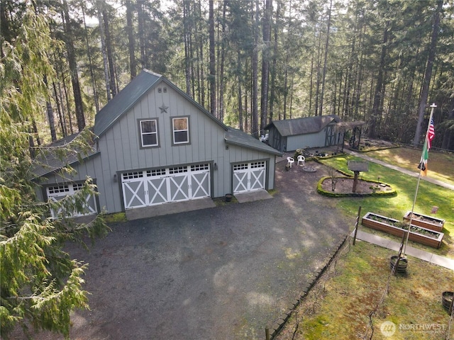 garage with dirt driveway and a forest view