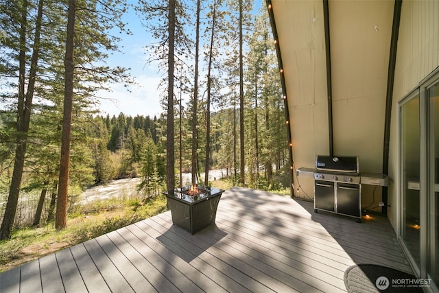 wooden deck featuring a grill and a forest view