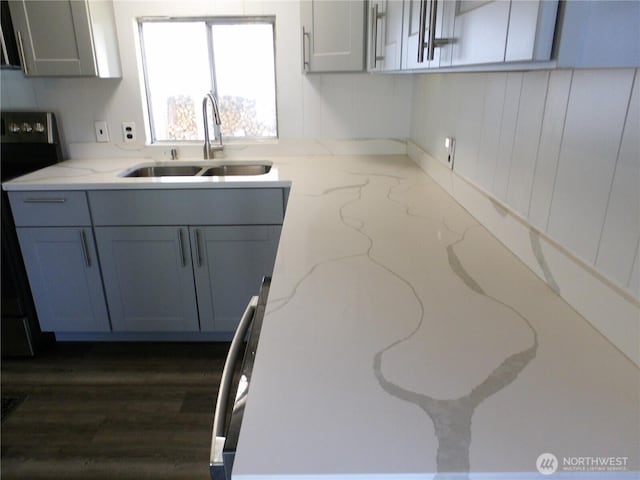 kitchen with gray cabinetry, light stone counters, electric stove, and a sink