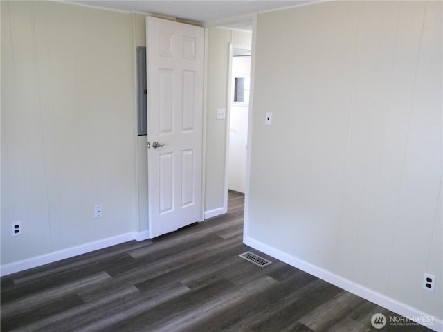 unfurnished room featuring baseboards, visible vents, and dark wood-type flooring
