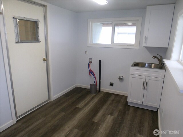 washroom with a sink, dark wood finished floors, baseboards, cabinet space, and hookup for a washing machine