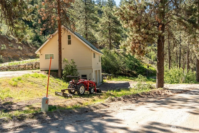view of home's exterior with a wooded view, driveway, and a garage