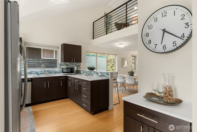 3924 S Brandon St Unit A, Seattle, WA 98118 - kitchen with dark brown cabinets, stainless steel appliances, a sink, and light wood-style floors