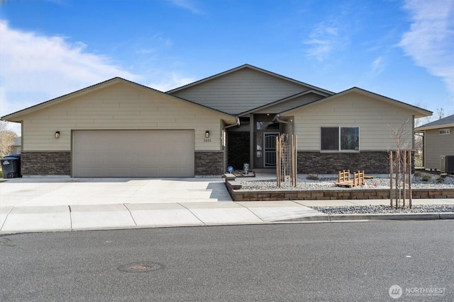 single story home with central AC, an attached garage, stone siding, and concrete driveway