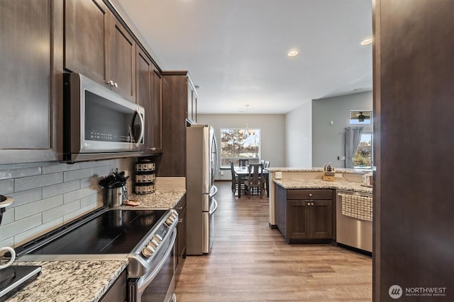 kitchen with stainless steel appliances, light wood-type flooring, backsplash, and dark brown cabinets