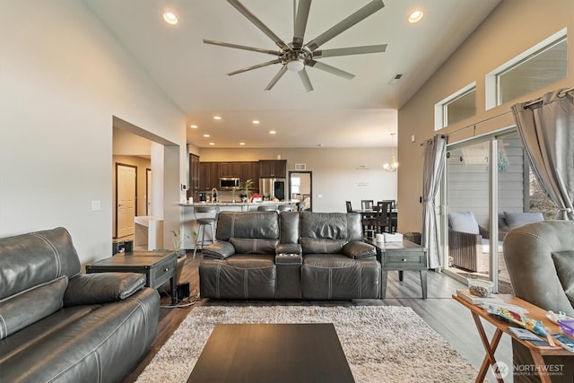 living room featuring visible vents, light wood-type flooring, a ceiling fan, recessed lighting, and high vaulted ceiling