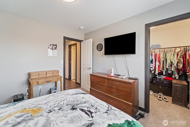 bedroom featuring a spacious closet, light carpet, and a closet