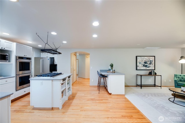 9300 138th Ct NE, Redmond, WA 98052 - kitchen featuring arched walkways, light wood finished floors, appliances with stainless steel finishes, and white cabinets