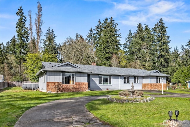 single story home with a chimney, fence, aphalt driveway, a shingled roof, and a front lawn