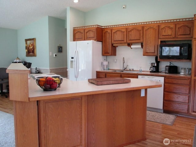 kitchen featuring white appliances, light countertops, brown cabinets, a sink, and light wood-style flooring