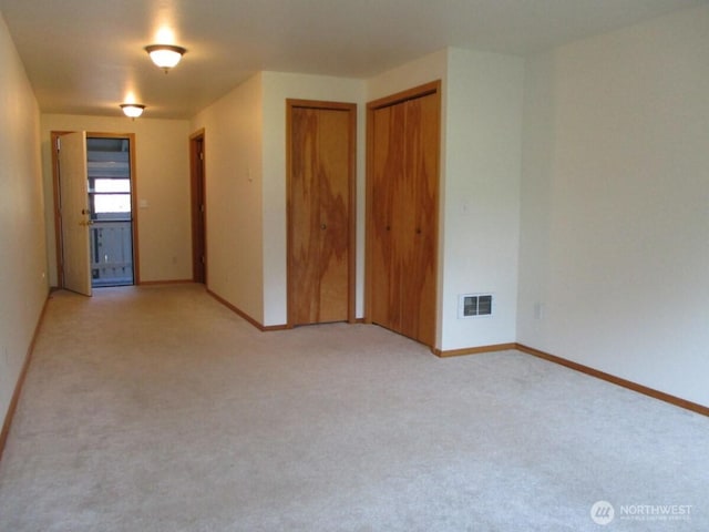 empty room with visible vents, baseboards, and light colored carpet