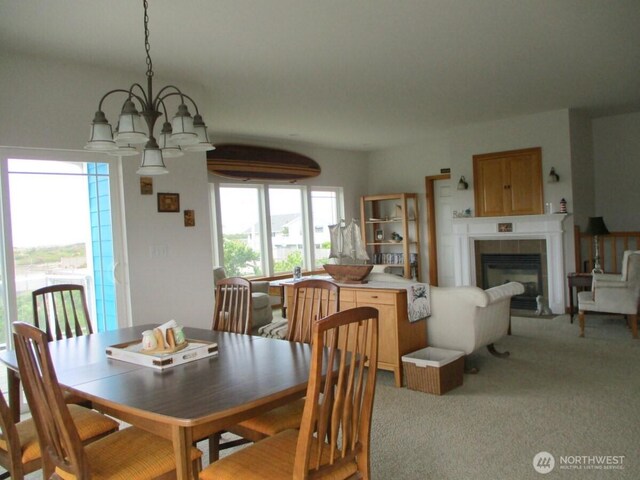 dining room with plenty of natural light, a tile fireplace, a chandelier, and light colored carpet