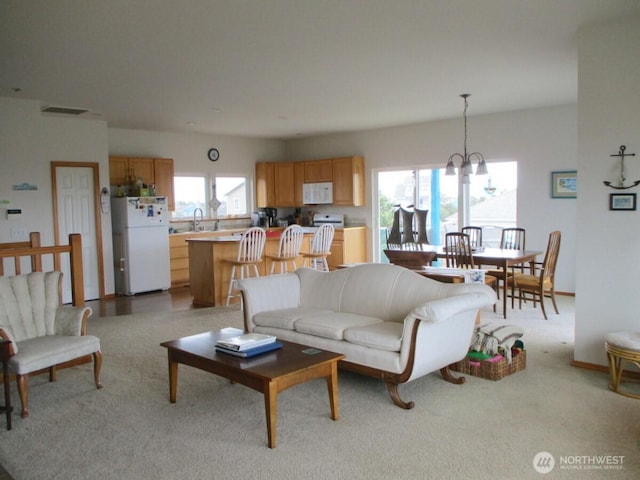 living area featuring visible vents, light colored carpet, and a notable chandelier