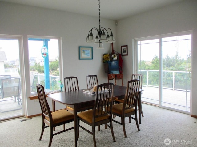dining room featuring visible vents, a healthy amount of sunlight, light carpet, and an inviting chandelier