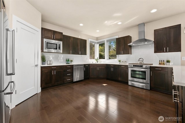 kitchen with dark brown cabinetry, appliances with stainless steel finishes, tasteful backsplash, light countertops, and wall chimney exhaust hood