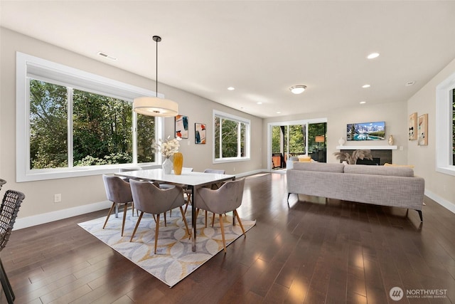 dining room with recessed lighting, baseboards, a fireplace, and dark wood finished floors