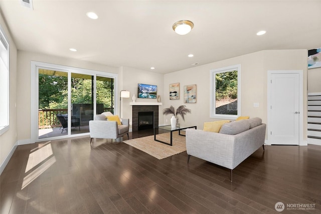 living room featuring a glass covered fireplace, dark wood-style floors, and a healthy amount of sunlight