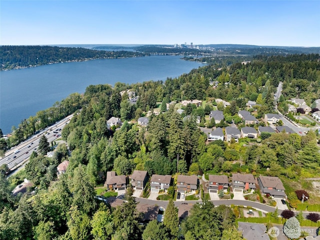 drone / aerial view with a residential view, a view of trees, and a water view