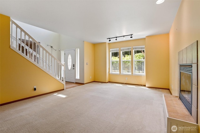 unfurnished living room with a tiled fireplace, baseboards, and carpet floors