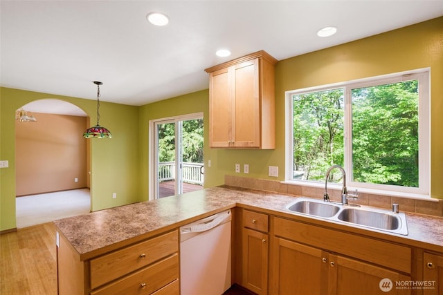 kitchen featuring light countertops, a peninsula, a sink, and dishwasher