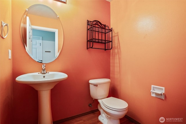 half bath with toilet, baseboards, and wood finished floors