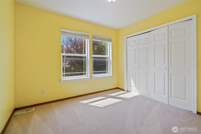 unfurnished bedroom with a closet, baseboards, carpet flooring, and visible vents