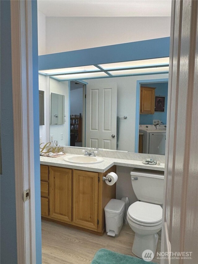 bathroom featuring independent washer and dryer, vanity, toilet, and wood finished floors