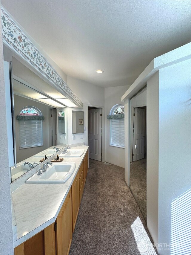 bathroom with double vanity, carpet floors, and a sink