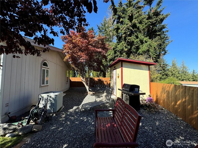 view of patio featuring an outbuilding, a storage unit, a fenced backyard, and grilling area