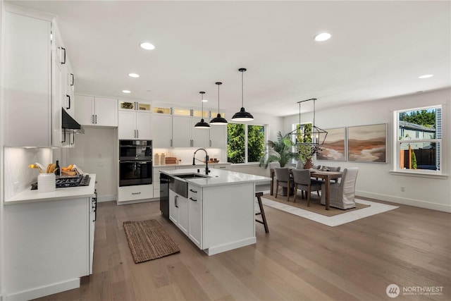 kitchen with a sink, black appliances, recessed lighting, backsplash, and white cabinets