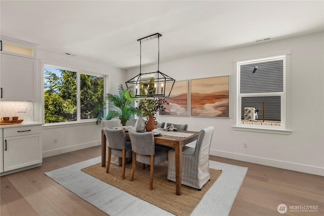 dining area with light wood finished floors, baseboards, and a chandelier
