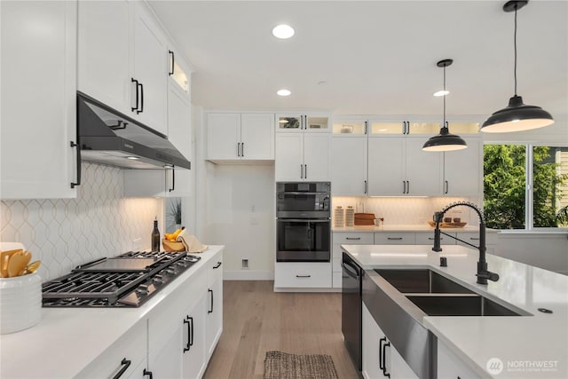 kitchen with under cabinet range hood, black dishwasher, gas cooktop, light countertops, and a sink