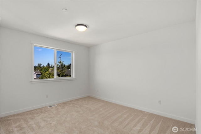 empty room featuring light colored carpet and baseboards