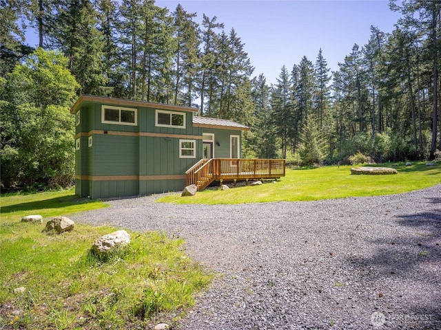 25 Eliza Ln, Lopez Island, WA 98261 - view of front of home with gravel driveway, a front yard, a deck, and a forest view