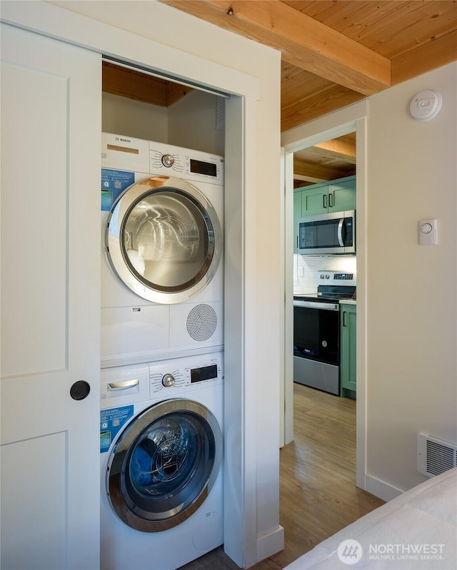 25 Eliza Ln, Lopez Island, WA 98261 - clothes washing area featuring visible vents, wood finished floors, laundry area, stacked washing maching and dryer, and wooden ceiling