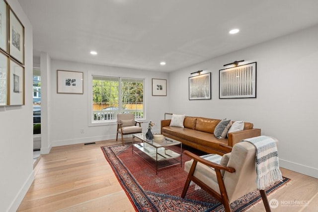 living room featuring visible vents, baseboards, recessed lighting, and light wood-style floors
