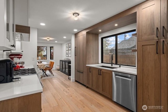 kitchen featuring stainless steel dishwasher, light wood-style flooring, recessed lighting, a sink, and light countertops